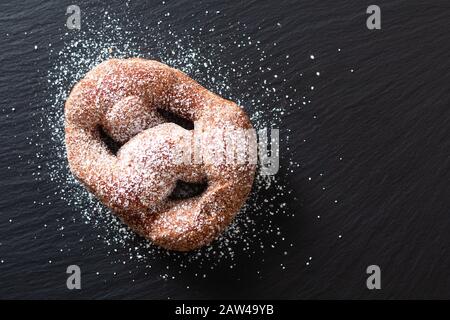Lebensmittelkonzept Single Beignet French Hefe Donut frittiertes Choux-Gebäck auf schwarzem Schieferplatten Hintergrund Stockfoto
