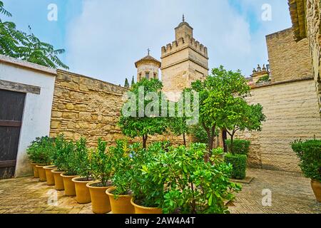 Kleiner Hof der Ölmühle Alcazar mit Pflanzen in Töpfen und Blick auf das antike Minarett einer Moschee und ihrer Kuppel, die mit dem Kreuz der Jungfrau Maria churc bekrönt ist Stockfoto