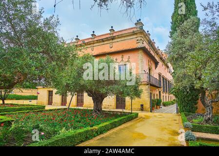 Jerez, SPANIEN - 20. SEPTEMBER 2019: Genießen Sie den schattigen andalusischen Garten von Alcazar mit Blick auf Blumenbeete, Topiarpflanzen, alte Olivenbäume und Wand o Stockfoto