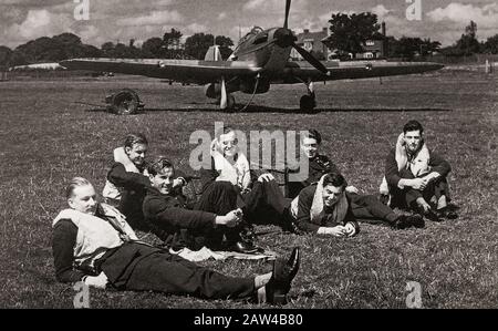 Piloten der 32 Squadron in Biggin Hill, Kent, England im Juli 1940, entspannend kurz vor den Eröffnungsschüssen der Schlacht um Großbritannien. Dahinter ein einsitziger Kampfflugzeug vom Typ Hawker Hurricane. Später wurde es im öffentlichen Bewusstsein von der Rolle der Supermarine Spitfire während der Schlacht um Großbritannien im Jahr 1940 überschattet, aber der Hurrikan fügte rund 70 % der Verluste der Luftwaffe im Engagement zu und kämpfte in allen großen Theatern des Zweiten Weltkriegs. Stockfoto