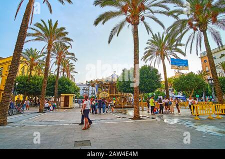 Jerez, SPANIEN - 20. SEPTEMBER 2019: Der Platz Plaza del Arenal hat viele Cafés, Bars und Vintage-Karussell; die Fußgängerzone ist mit üppigen Palmen dekoriert, bis Stockfoto