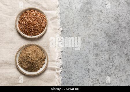 Gemahlene braune Leinsamen oder Leinsamen in Schüsseln auf grauem Steintisch. Draufsicht. Leerzeichen für Text. Gesundheit und Entgiftung. Gewichtsverlust. Stockfoto