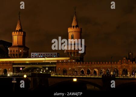 Die Brücke Oberbaumbrücke an der Spree verbindet nachts Ost- und Westteil Berlins mit einer Bahn, die in langer Belichtung vorbeiführt Stockfoto