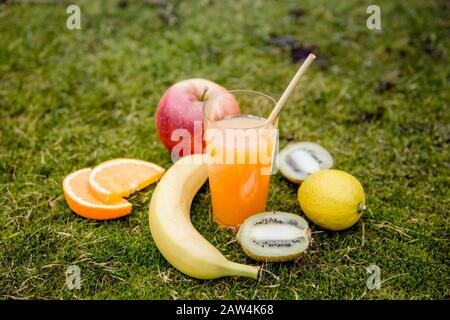 Bambus trinkt Strohhalm in gemischtem Saft und viele verschiedene süße Früchte auf natürlichem weichem grünem Moos im Freien. Geringe Tiefe von Feld und Kopierer Stockfoto