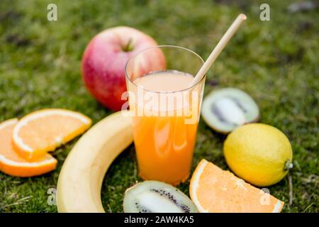 Bambus trinkt Strohhalm in gemischtem Saft und viele verschiedene süße Früchte auf natürlichem weichem grünem Moos im Freien. Geringe Tiefe von Feld und Kopierer Stockfoto