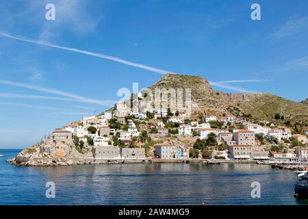 Hügel auf der Insel Hydra in Griechenland am Eingang zum Hafen mit weiß getünchten Häusern und Steingebäuden. Stockfoto