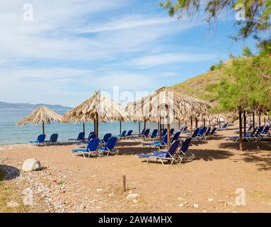 Vlichos Strandszene auf Hydra Island, Griechenland mit Liegestühlen und Palapas. Stockfoto