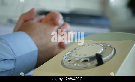 Geschäftsmann am Arbeitsplatz mit einem Alten Telefon am Schreibtisch, Das Einen Telefonanruf Abwartet Stockfoto