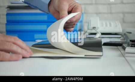 Bild mit einem Unternehmer, Der Im Büro arbeitet. Durchsuchen Sie die Agenda-Seiten, Und Suchen Sie Nach Schriftlichen Notizen Stockfoto