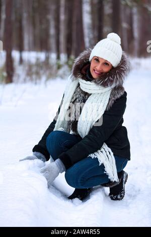 Frau, die in einem Winterwald mit Schnee spielt. Fröhliche Dame macht einen Schneeball Stockfoto