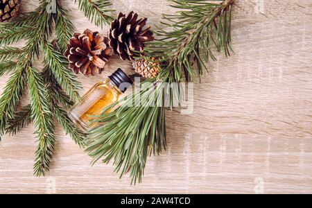 Aromaölflasche aus Kiefer und Tannenbaum mit Kiefern und Tannenästen zur Dekoration auf Holzhintergrund. Ätherisches Ölkonzept. Stockfoto