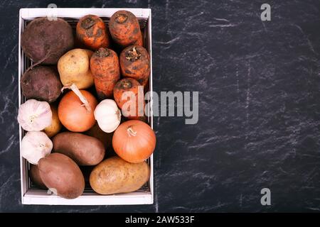 Frisches Gemüse in Holzkiste auf schwarzem Grund Stockfoto