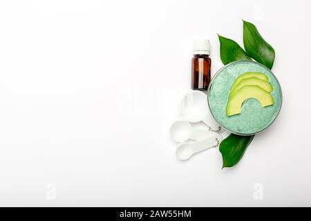 Avocado Gesichtsmaske in Glasbecher, hausgemachte Nährmaske aus gestampftem Avocado, ätherisches Öl, Löffel. Heimwerker-Kosmetik-Rezept, Hautpflege Stockfoto