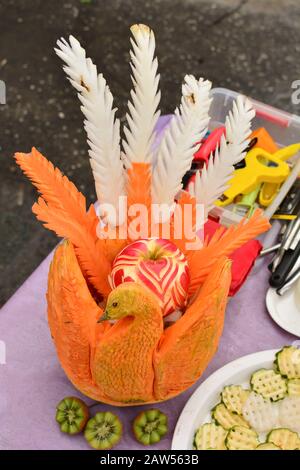 Kunstvoll geschnitzter orangefarbener Kürbis, Pfauenform mit weißer und orangefarbener Pflaume Stockfoto