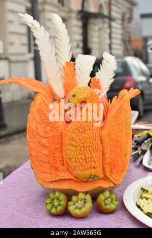 Kunstvoll geschnitzter orangefarbener Kürbis, Pfauenform mit weißer und orangefarbener Pflaume Stockfoto