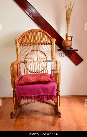 Wicker Schaukelstuhl auf Holzparkett, als Teil des Innenraums der Blockhütte Stockfoto