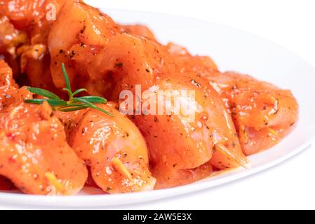 Rohe Hühnerflügel in einer Marinade mit Gewürzen auf einem weißen Teller. Hähnchenfleisch aus nächster Nähe.Isolate.Draufsicht. Stockfoto