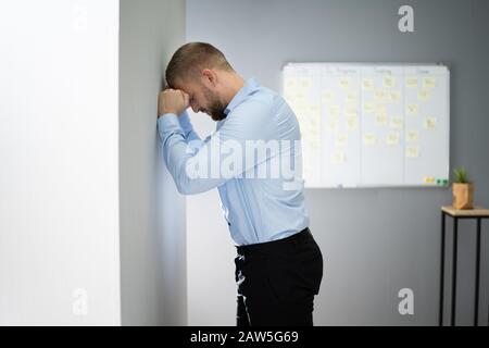 Portrait von Enttäuscht Geschäftsmann lehnte sich an der Wand im Büro Stockfoto