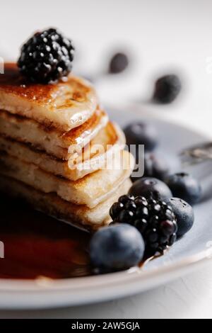Nahaufnahme von flauschigen hausgemachten Pfannkuchen mit Sirup und Beeren Stockfoto