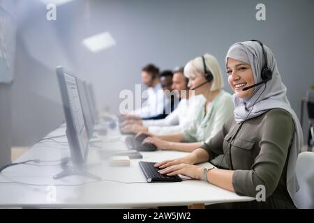 Positive weibliche Kunden Services Agent mit Headset das Arbeiten in einem Call Center Stockfoto