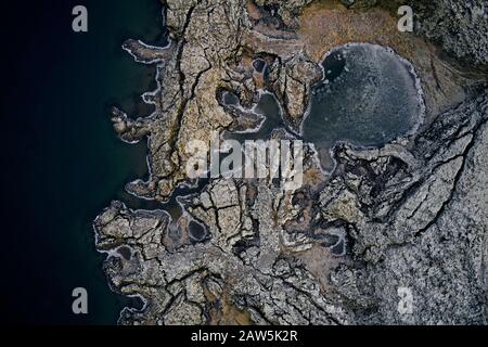 Draufsicht über die raue felsige Küste mit Lagune in der Nähe von ruhigem Meerwasser in der Natur Stockfoto