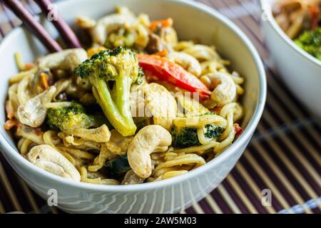 Nahaufnahme von gelber Curry rührgebratener thai-nudeln-Schüssel mit Gemüse, Huhn, Rindfleisch und Cashews Stockfoto