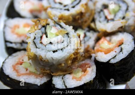 Bild einer Nahaufnahme von Maki-Sushi aus Reis, Avocado, Gurken, Garnelen, gebratener Zwiebel und Nori-Algen Stockfoto