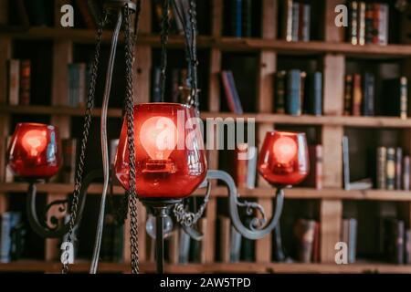 Leuchtrekandelaber in der Bibliothek. Rote Lampen leuchten mit Büchern auf einem Hintergrund. Stockfoto