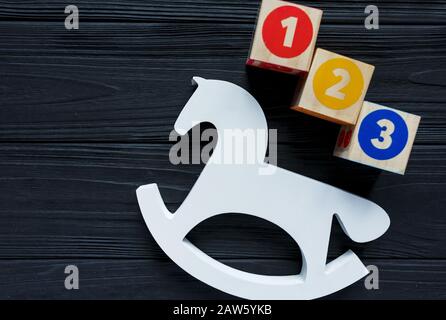 Holz-Weiß-Pferd, Blöcke, Spielzeuge für die Kreativitätsentwicklung auf schwarzem Hintergrund. Bildungsspiele für Kindergarten, Vorschulkinder. Stockfoto