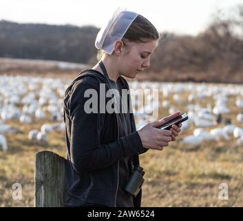 Lancaster County, Pennsylvania, USA: 3. Februar 2020: Junge Amish-Frauen in schwarzem Kleid und weißer Haarbedeckung mit Handy Stockfoto