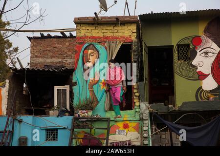 Neu-Delhi, Indien. Februar 2020. Eine Frau kommt aus ihrem Haus, das am 6. Februar 2020 in einem Slum in Neu-Delhi, Indien, mit Wandbildern bemalt wurde. Ein Neu-Delhi Slum wurde von einer lokalen Gruppe bunt umgestaltet. Credit: Javed Dar/Xinhua/Alamy Live News Stockfoto