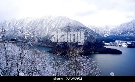 Hallstatt-Traumlandschaft Winter Schnee Berglandschaft Outdoor-Abenteuer mit blauem Himmel und Pinien im Vordergrund im verschneiten Tag, Österreich Stockfoto