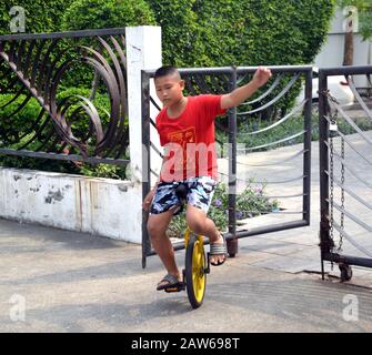 Ein junger asiatischer Junge im Alter von 12 bis 13 Jahren praktiziert das Reiten eines Monokelkens in Bangkok, Thailand, Südostasien. Stockfoto