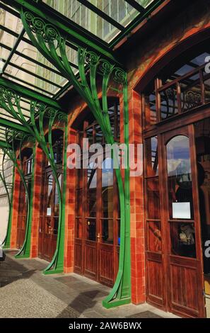Kunstvoll verzierte Bügel aus organischem Jugendstil stützen die Glasfenster neben hohen Eichentüren am Vordereingang des Prager Hauptbahnhofs Stockfoto