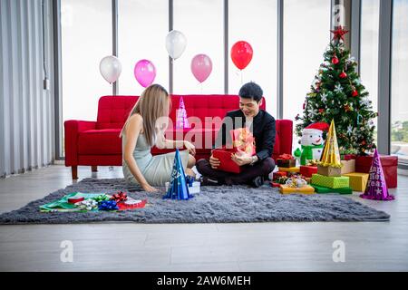 Asiatische Paarliebhaber schenken im Weihnachtsurlaub eine Geschenkbox mit Weihnachtsgeschenk und fröhlicher Neujahrspatze Stockfoto