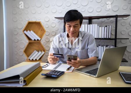 Asiatischer Mann, der online mit dem Smart-Phone einkauft und mit Kreditkarte bezahlt Stockfoto