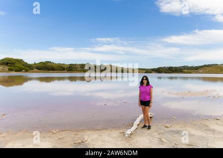 Ein weiblicher Wanderer macht eine Pause am Pink Lake Beach auf Rottnest Island in Western Australia. Stockfoto