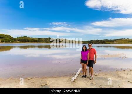 Ein Paar, das auf Rottnest Island in Western australia radeln, machen eine verdiente Pause am Ufer des Pink Lake. Stockfoto