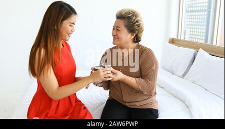 Asiatische Frauen pflegen und Geben Der älteren Frau Pillen oder Medikamente, um zu Hause zu essen Stockfoto