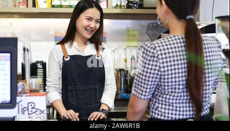 Barista, der Kunde und Frau bedient, bezahlt Kaffee per Kreditkarte im Café Stockfoto