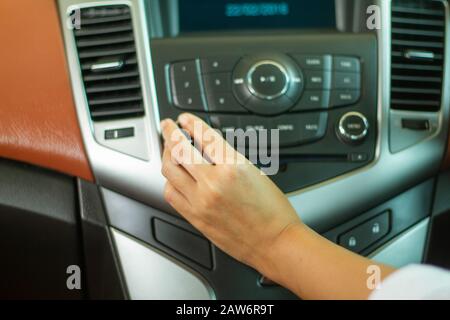 Asiatische Frauen Taste am Autoradio für die Wiedergabe von Musik. Stockfoto