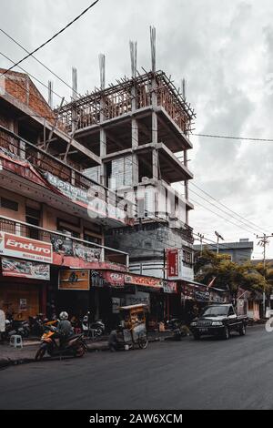 Manado, NORTH SULAWESI, INDONESIEN - 5. AUGUST 2015: Straße von Manado mit unvollendetem Gebäude im Hintergrund am 5. August 2015 in Manado, North Sul Stockfoto