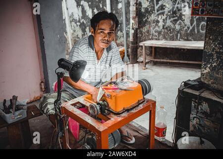 Manado, NORTH SULAWESI, INDONESIEN - 5. AUGUST 2015: Mann mit Schleifmaschine, der am 5. August 2015 in Manado, North Sulawe auf der Straße von Manado arbeitet Stockfoto