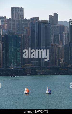 Kleine Jachten werden von den hohen Gebäuden in Kowloon Bay, Hongkong, China, in den Schatten gestellt Stockfoto