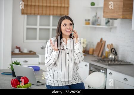 Langhaarige Frau in einer gestreiften Bluse, die am Telefon spricht Stockfoto