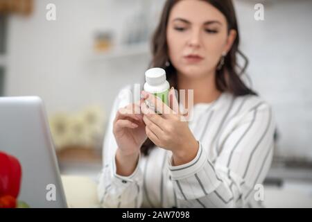 Dunkelhaarige Frau in einer gestreiften Bluse, die nachdenklich aussieht Stockfoto