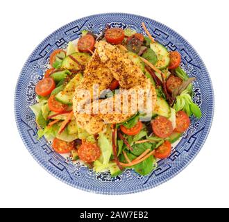 Frischer Hühnersalat auf einem blau dekorierten Teller, isoliert auf weißem Hintergrund Stockfoto
