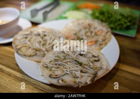 Traditioneller vietnamesischer Banh Xeo Imbiss mit Reiskrackern mit Pilzen, Meeresfrüchten und Sprossen Stockfoto