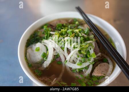 Nahaufnahme der traditionellen vietnamesischen Pho-Suppe in einer Schüssel mit Holzstäbchen Stockfoto