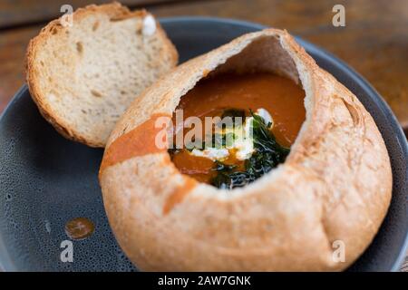 Tomatensuppe in Brot mit saurer Sahne und Grüns aus nächster Nähe, Lebensmittelhintergrund Stockfoto